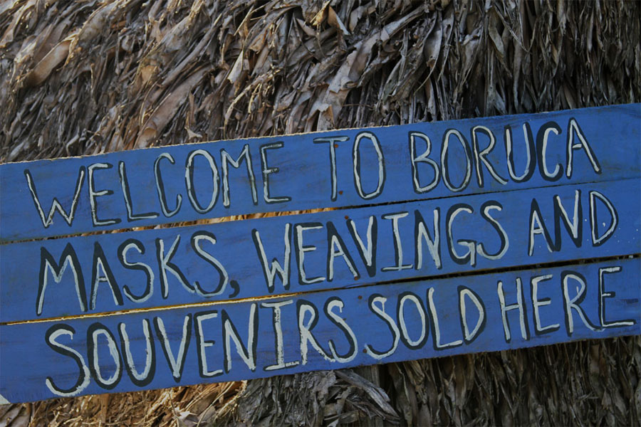 A hand-made sign welcomes visitors and community members to a local shop to purchase original masks and other exquisite crafts.